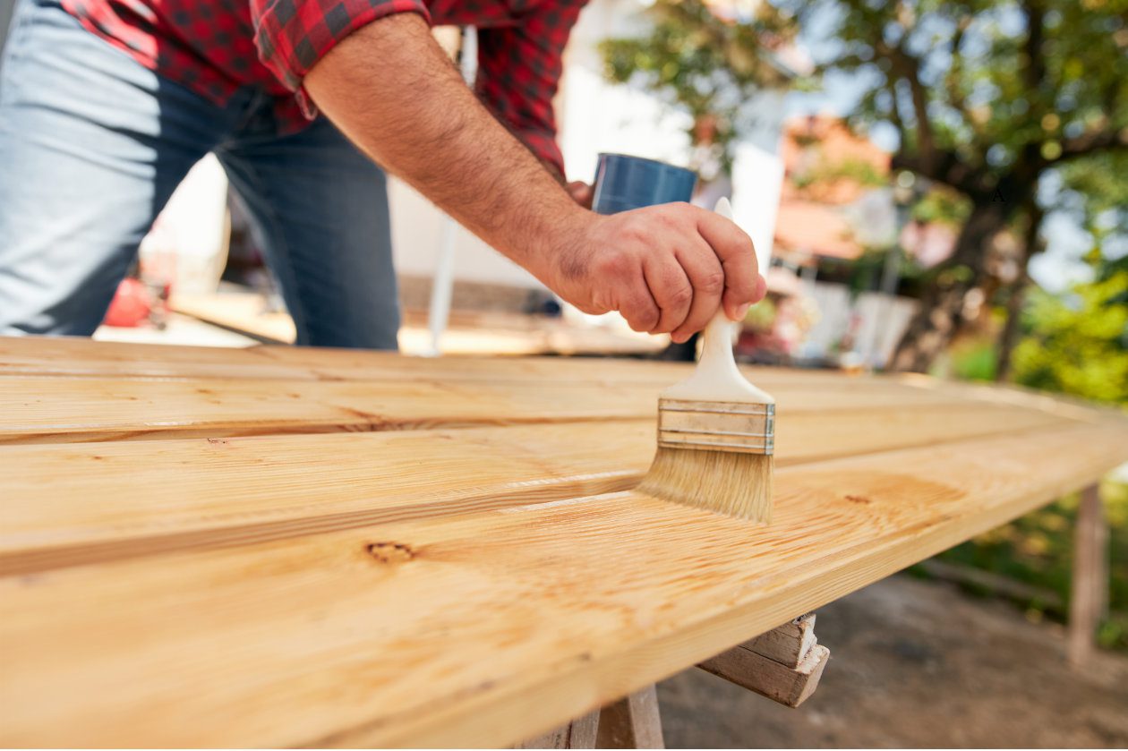 Bútor lakkozás: Egy kéz fa felületet lakkoz
